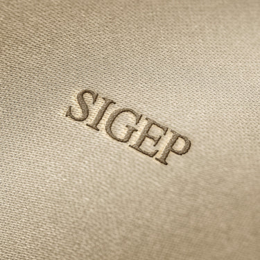 Soft beige fabric close-up showing a smooth, heavyweight knit texture with gentle folds and subtle draping.