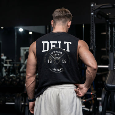 Man wearing a black cut off tank with premium grunge gym design