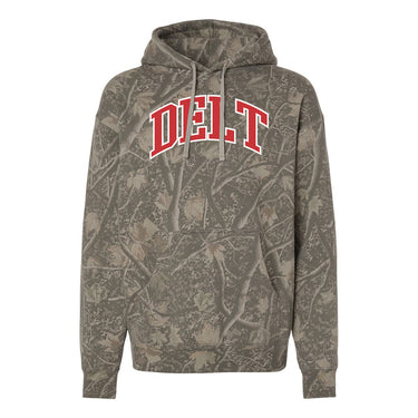 College-aged male wearing the fraternity Deadwood Camo Hoodie with red and white Delta Tau Delta lettering, seated outdoors in a wooded setting.