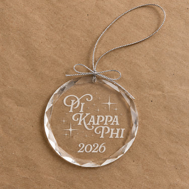 2026 Limited Edition clear glass holiday ornament featuring engraved fraternity design and silver hanging string