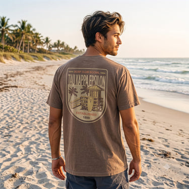 Model wearing the Surf Club Social T-shirt from the back while walking on a beach.