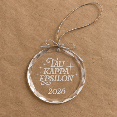 2026 Limited Edition clear glass holiday ornament featuring engraved fraternity design and silver hanging string