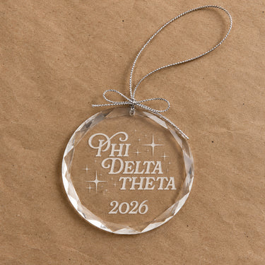 2026 Limited Edition clear glass holiday ornament featuring engraved fraternity design and silver hanging string