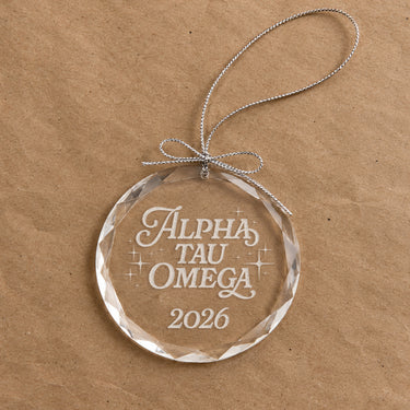 2026 Limited Edition clear glass holiday ornament featuring engraved fraternity design and silver hanging string
