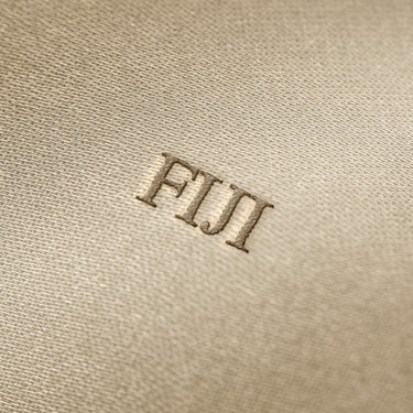 Soft beige fabric close-up showing a smooth, heavyweight knit texture with gentle folds and subtle draping.