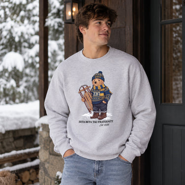 Man wearing a grey crewneck with festive fraternity bear design