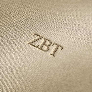 Soft beige fabric close-up showing a smooth, heavyweight knit texture with gentle folds and subtle draping.