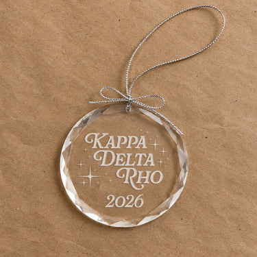 2026 Limited Edition clear glass holiday ornament featuring engraved fraternity design and silver hanging string