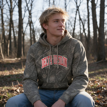 DU Deadwood Camo Hoodie featuring an all-over woodland camouflage print, red and white arched Delta Uspilon lettering, drawstring hood, and kangaroo pocket.