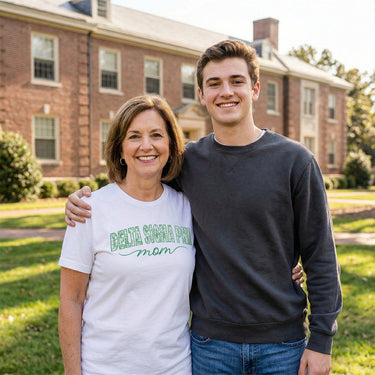 Mom wearing a white t-shirt with a mom graphic tee standing with her fraternity son.