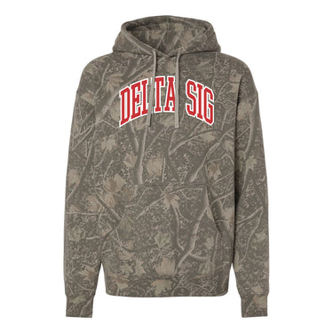 College-aged male wearing the fraternity Deadwood Camo Hoodie with red and white Delta Sigma Phi lettering, seated outdoors in a wooded setting.